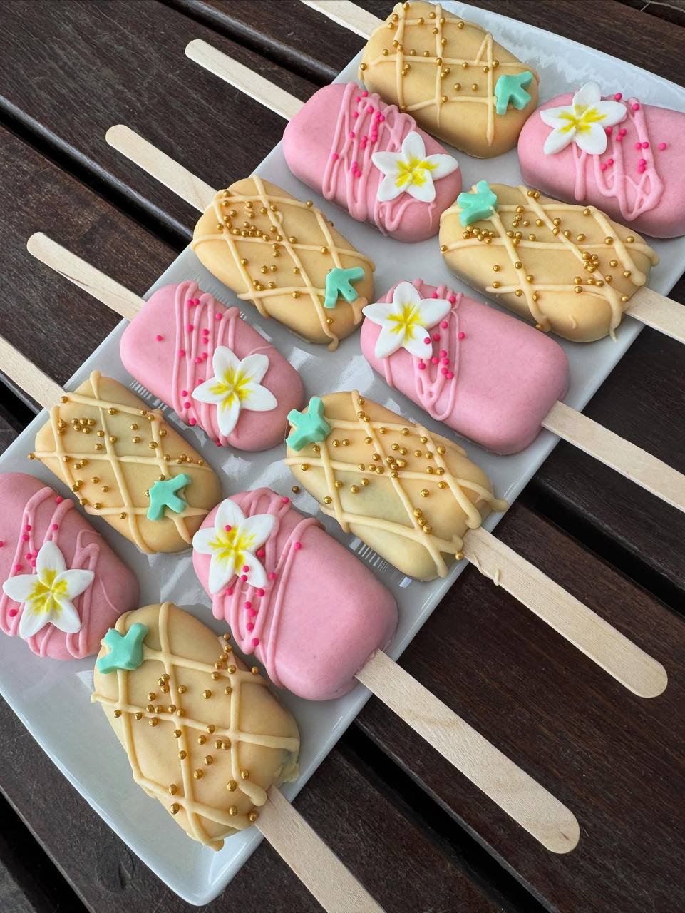 Elegant pink and gold cakesicles with floral decorations